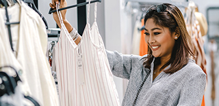 Person holding a light-colored, sleeveless striped dress on a hanger