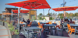 Outdoor dining area with multiple tables and bright orange umbrellas